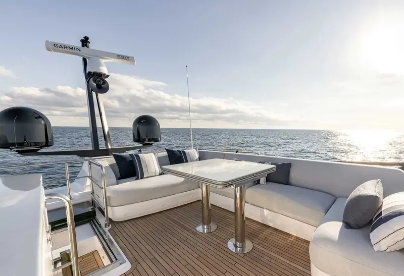 The aft flybridge seating and cocktail table, with the mast-mounted radar and antennas visible against open water.