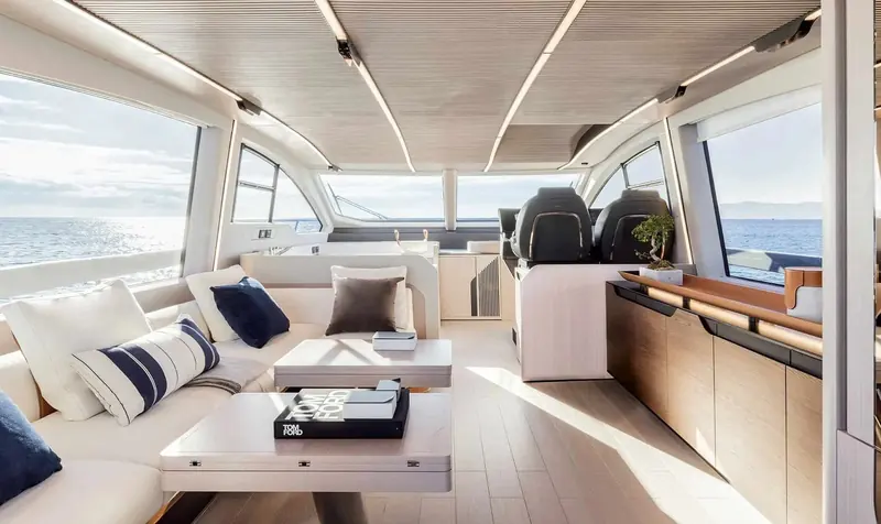The main salon looking aft toward the lower helm, with an L-shaped sofa, twin coffee tables and a full-beam wood and leather galley unit to starboard.