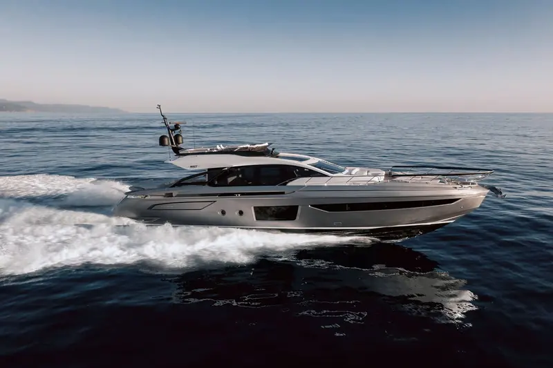 Running broadside against a hazy coastline, the low sheerline and glazed superstructure showing the coupe profile that separates the S range from Azimut's flybridge boats.