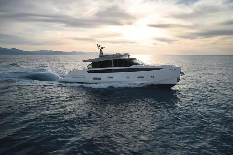Underway at sunset, the open flybridge helm station visible above the wraparound windscreen.