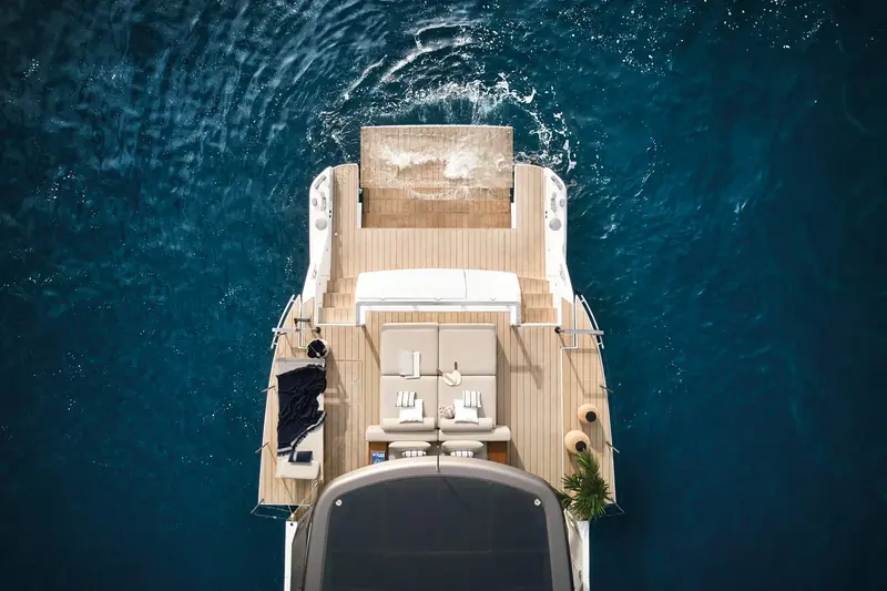 The starboard walkway and hull glazing seen close up, lit portholes running the length of the lower-deck cabins.