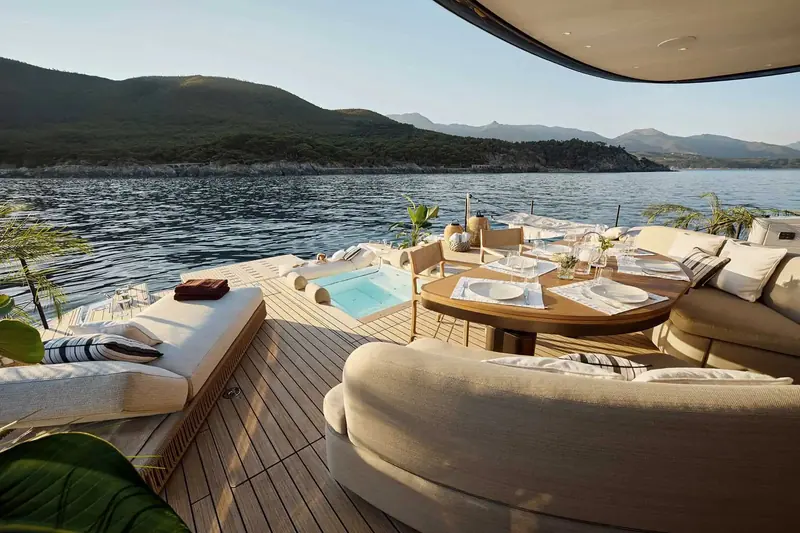 The aft lounge and sunken pool seen from the side terrace, coastline behind - the open-air living the whole Seadeck line is built around.