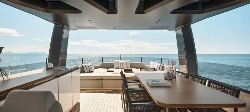 The saloon dining area, full-height glass on both sides pulling the sea into the room.