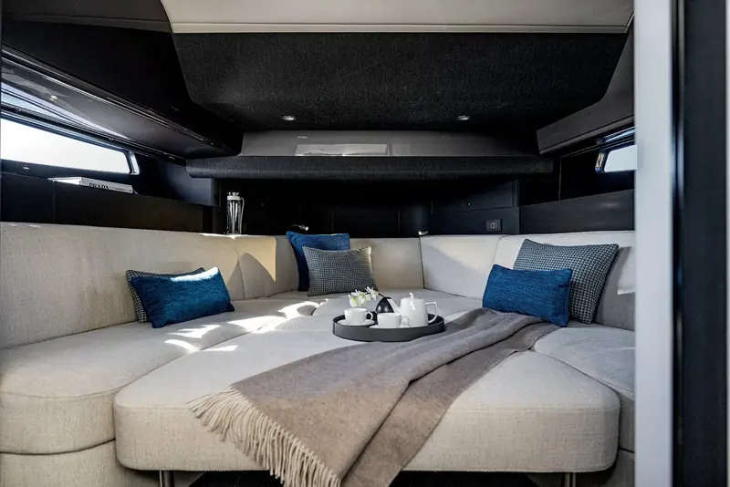 The below-deck cabin's L-shaped settee made up with a throw and a tea tray, lit by the black-glazed hull windows either side.