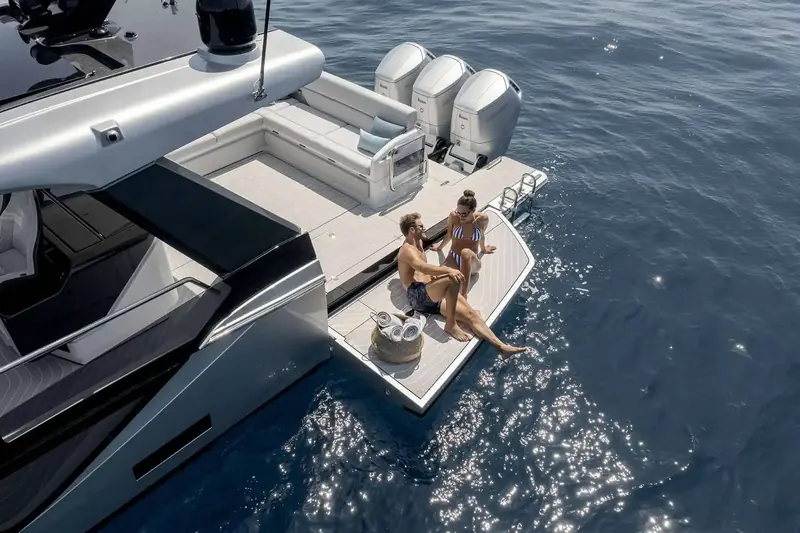 Overhead, the fold-down transom platform used as its own sunning and swim deck, engines and helm seating forward of it.