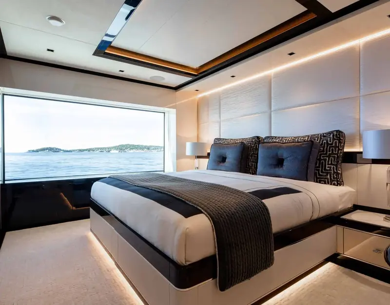 A guest cabin with a full-height window framing a Mediterranean island, black and cream joinery throughout.