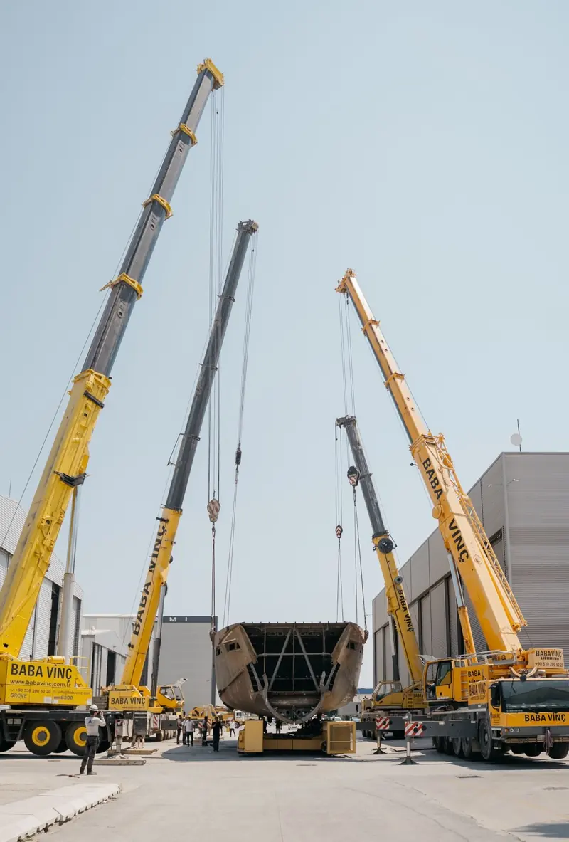Three cranes take the weight of the hull for the turnover, the move that flips a hull from upside-down build position to upright