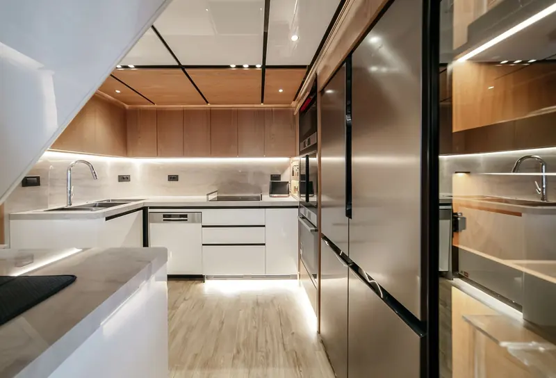 The galley runs full-beam with a central island, built for a boat that expects to feed 11 guests on a long passage rather than a weekend.