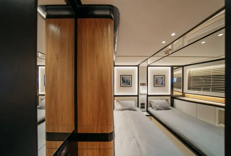 A twin cabin in dark wood panelling, one of five guest cabins the 88 carries alongside separate crew quarters.