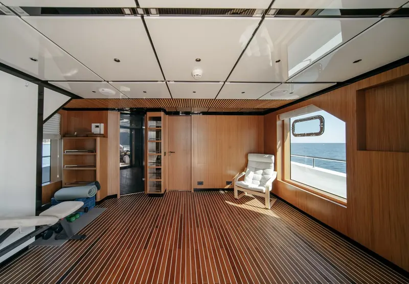 A dedicated gym compartment below decks, teak-floored and fitted into the hull rather than bolted onto a deck as an afterthought.
