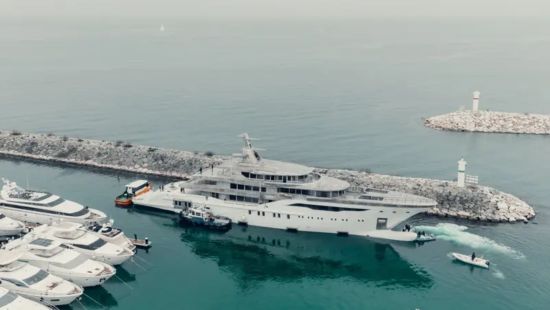 Hull NB77, the 73.6-metre Bilgin 243, passes the West Istanbul Marina breakwater lighthouse under tow during her January 2022 technical launch, her superstructure still in bare unfinished aluminium.