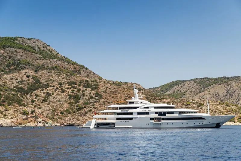 Chopi Chopi under way past Hydra island in the Aegean, her tiered Zuccon profile stepping cleanly down from the sundeck to the tender garage aft.