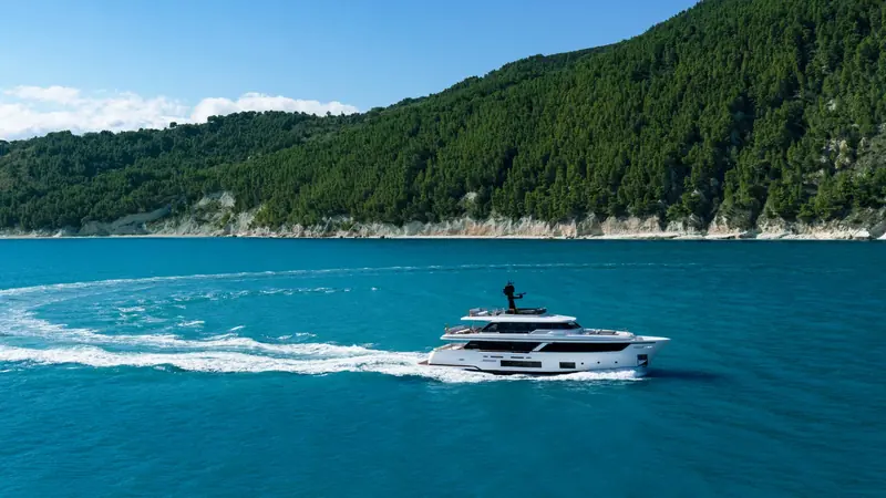 The Navetta 30 running close to shore, showing its full-displacement hull and raised pilothouse.