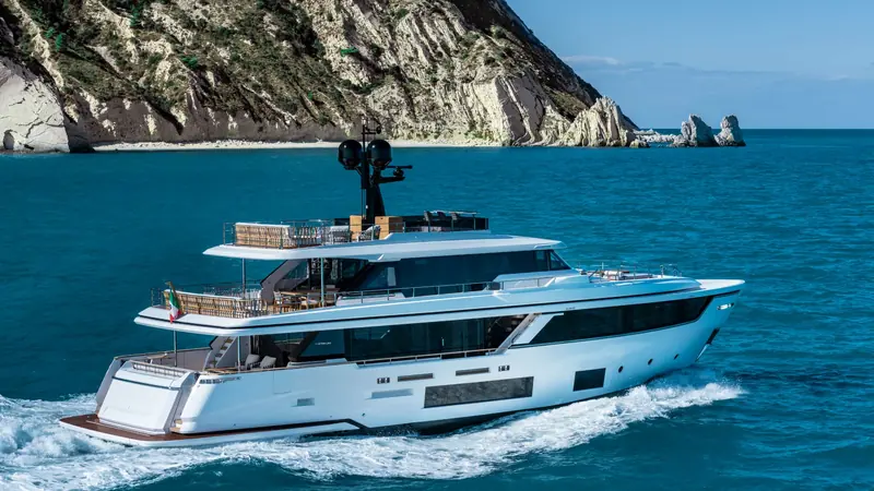 The Navetta 30 under way along a rocky coastline.