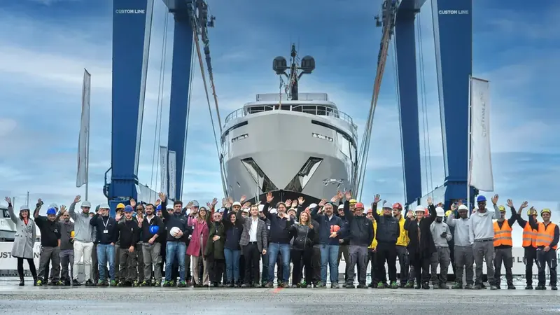 A Navetta 30 hull at its launch ceremony, lifted by gantry crane at the Custom Line yard.