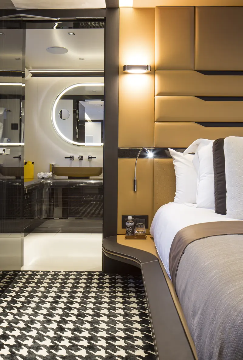 A guest cabin's Pepita houndstooth carpet, lifted directly from the Porsche 911 R's interior fabric, set against tan leather headboard panelling with carbon-fibre trim strips.
