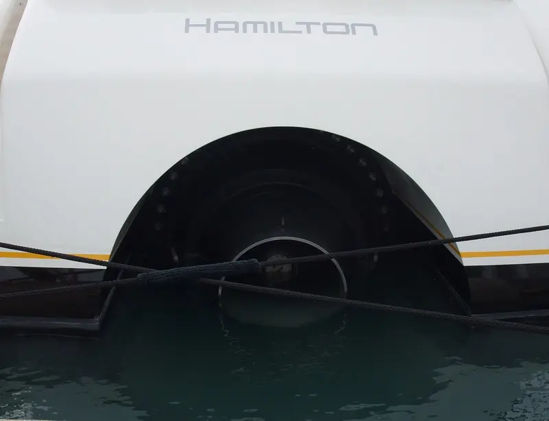 A bow-thruster tunnel seen close from the tender. The black rubber fendering around the opening is standard on a yacht this size, protecting the hull plating during close-quarters docking.