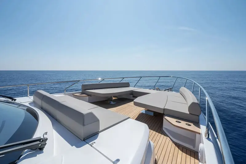Foredeck seating and sunpad, shot from the bow rail looking aft to the flybridge overhang.