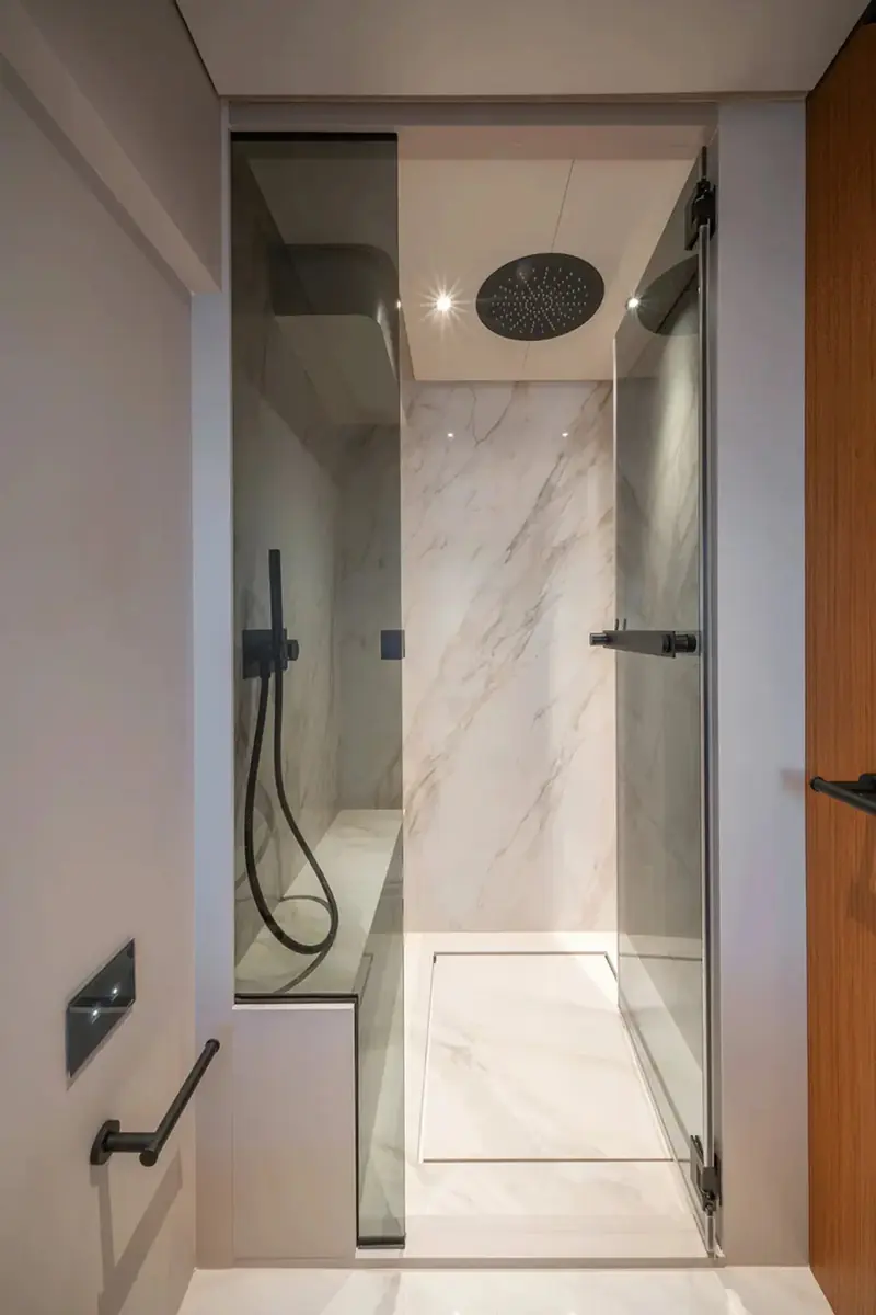 A glass-walled ensuite shower, marble-effect surfaces standard across the accommodation deck.