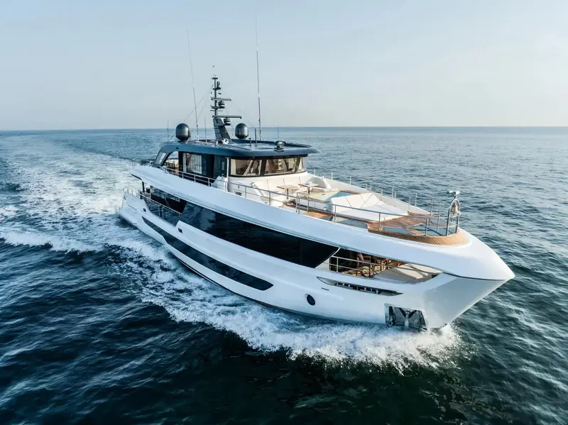 A second Dubai Marina pass under full power, twin symmetrical wakes and a teak-decked foredeck lounge open to the sky ahead of the wheelhouse.