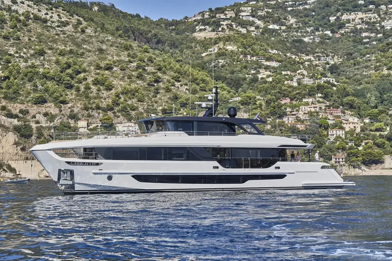 At anchor off the wooded hills above Monaco, the low, sheer black window band running the full length of the hull.