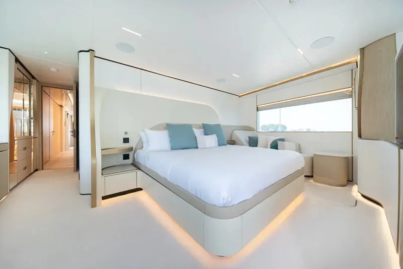 The owner's cabin, a full window strip along one side and warm underlighting traced around the base of the bed platform.