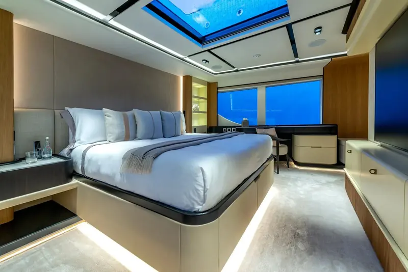A guest cabin finished in pale wood with concealed LED lighting along the berth, matching the fit-out level of the boat's owner's suite.