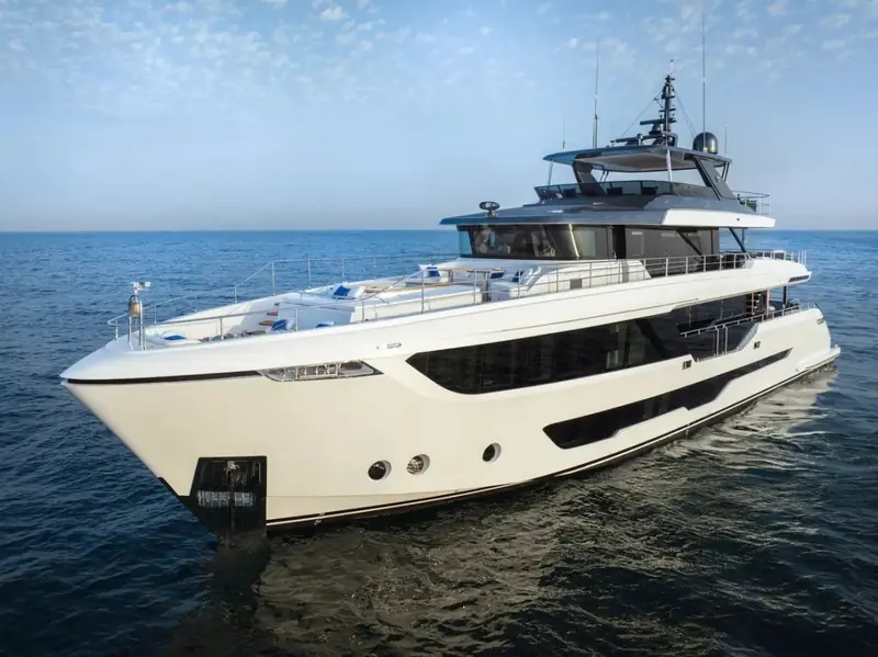 At rest in flat water, the low freeboard aft and the full-beam glazing along the main deck salon both clearly visible.