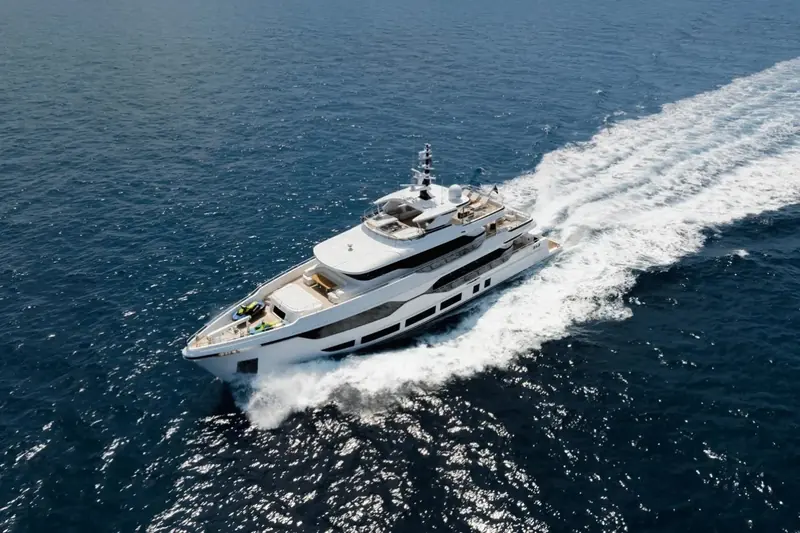 A drone pass on the wake shows the beam carried well aft and the raised bulwarks around the bow sunpad - practical freeboard for a yacht built to cross open water, not just coast-hop.