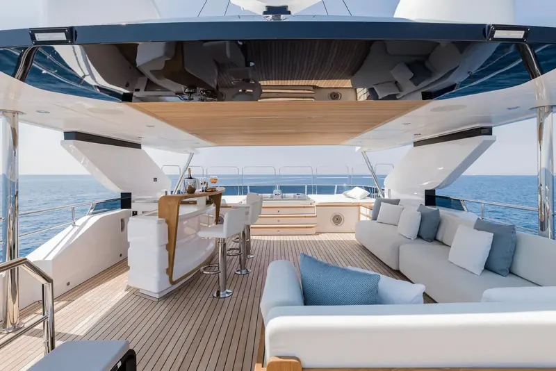 The flybridge bar and lounge looking aft, shaded by the hardtop with its glossy underside reflecting the deck below. This upper deck social space is one of the layout choices Gulf Craft lets owners rework hull to hull.