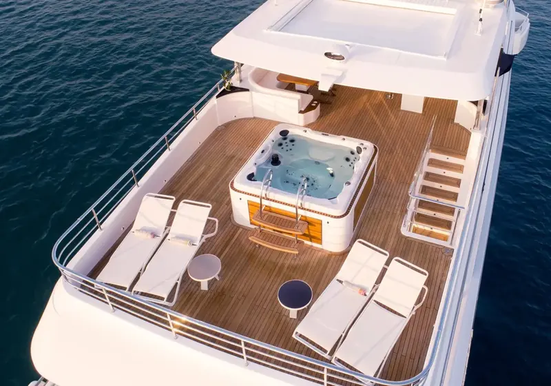 The flybridge carries a full-size jacuzzi and sun loungers, the boat's main open-air entertaining deck above the bridge.