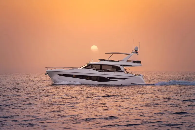 Majesty 60 running into a low sun, hull and flybridge shown in dramatic silhouette against the glare on the water.