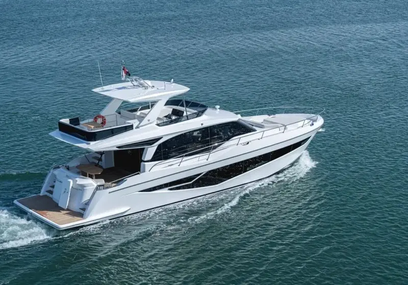 Cruising past a distant skyline with birds skimming low over the water, giving a sense of the hull's real-world scale.