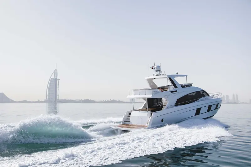At speed and up on plane past the Burj Al Arab, the deep vee bow throws a clean, contained wake typical of Gulf Craft's flybridge hull design.