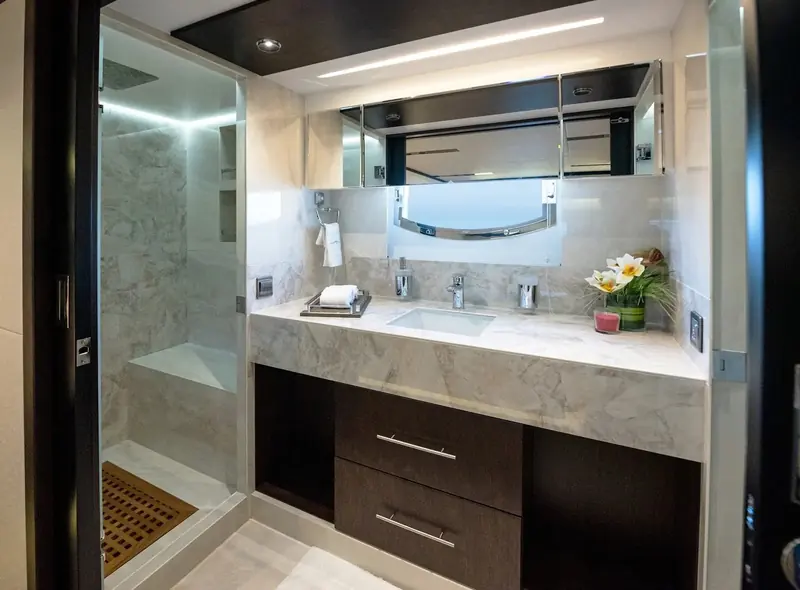 An en-suite bathroom finished in marble-effect stone, one of the details that separates the 62M's fit-out from a standard flybridge motor yacht in its size class.
