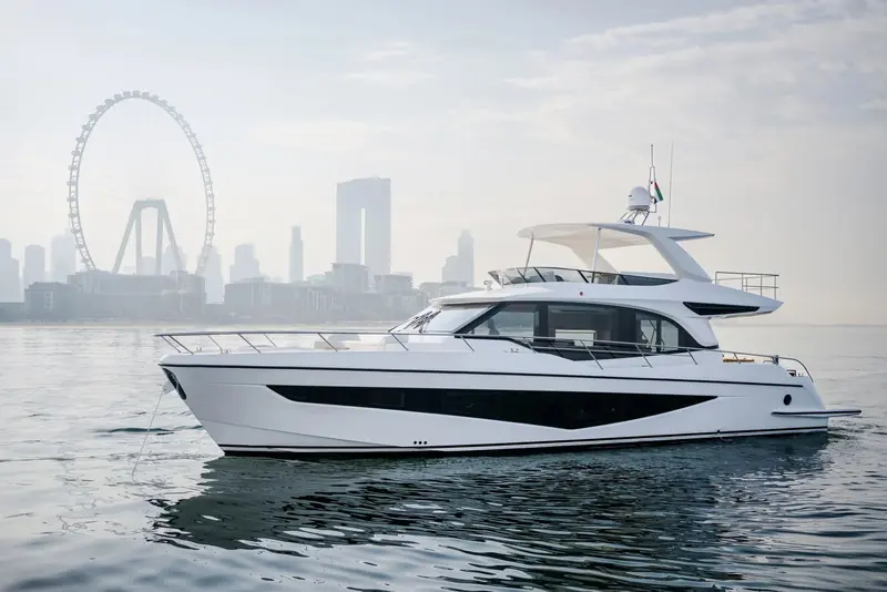 Majesty 65 running into a low orange sun, her flybridge hardtop and raked windscreen picked out in silhouette.