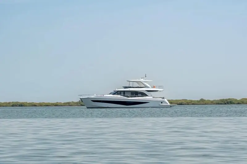 Under way at speed with the flybridge T-top open on all sides, throwing a wide planing wake astern.