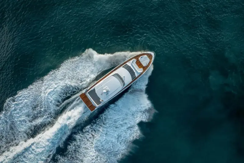 At rest in flat water with a flock of birds passing low overhead, the full length of the hull shown in clean profile.