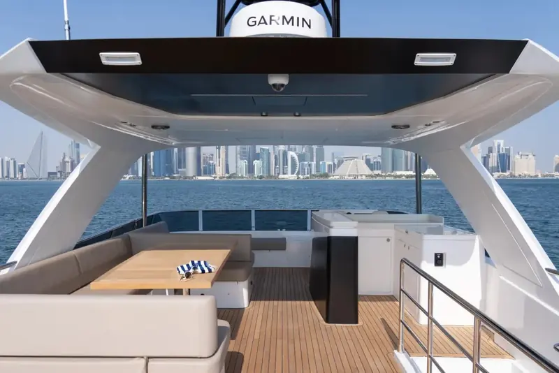 The flybridge helm station and hardtop framework under way, a Garmin radome mounted on the arch above and a city skyline astern.