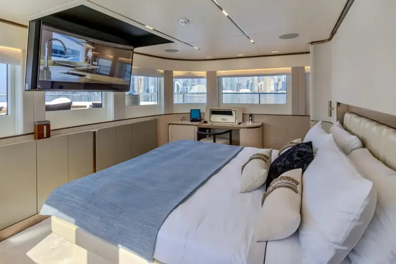 A day-cabin fitted with its own desk and wall-mounted screen, windows running the full width of the hull side.