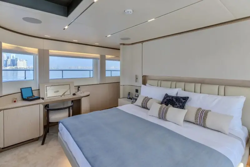 A twin-bed guest stateroom finished in pale blue and cream, a small desk built into the hull-side wall.