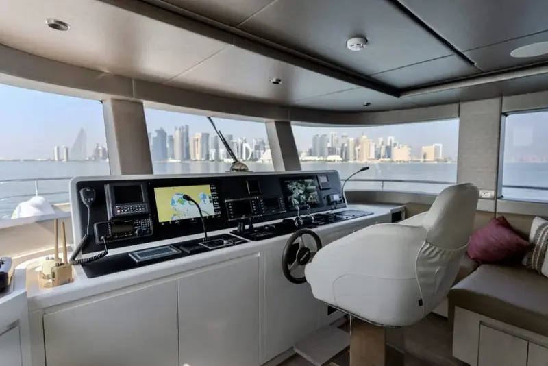 The helm under way with the Doha skyline behind, crew and guests seated together around the raised companion chair.