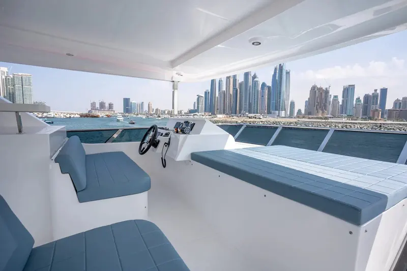 At anchor with davits and a stowed tender visible aft, the flybridge hardtop and full-beam saloon glazing shown in profile.