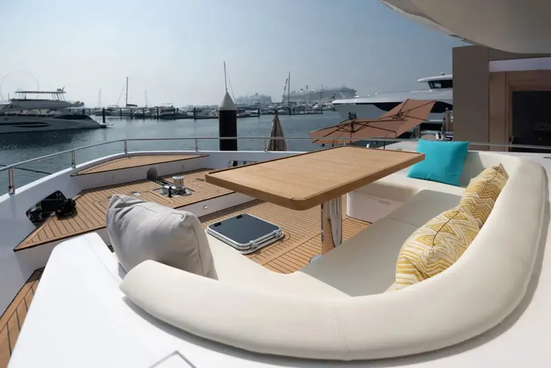The bow lounge alongside: a C-shaped settee around a teak table, the social space a 21-metre boat wins by keeping her foredeck clear.