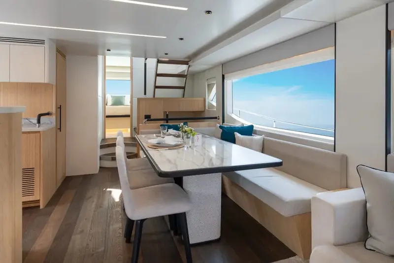Dining for eight amidships on the main deck, with the galley pass and the stair to the lower accommodation immediately behind it.