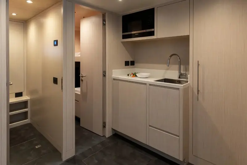 A compact galley tucked beside the lower stairwell, fitted with an induction hob and full-size sink rather than a boat-camping setup.