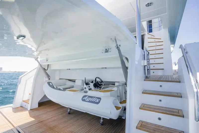The tender garage open at the stern, a small rigid inflammable branded Agilis stowed on its launching cradle beside the boarding stairs.