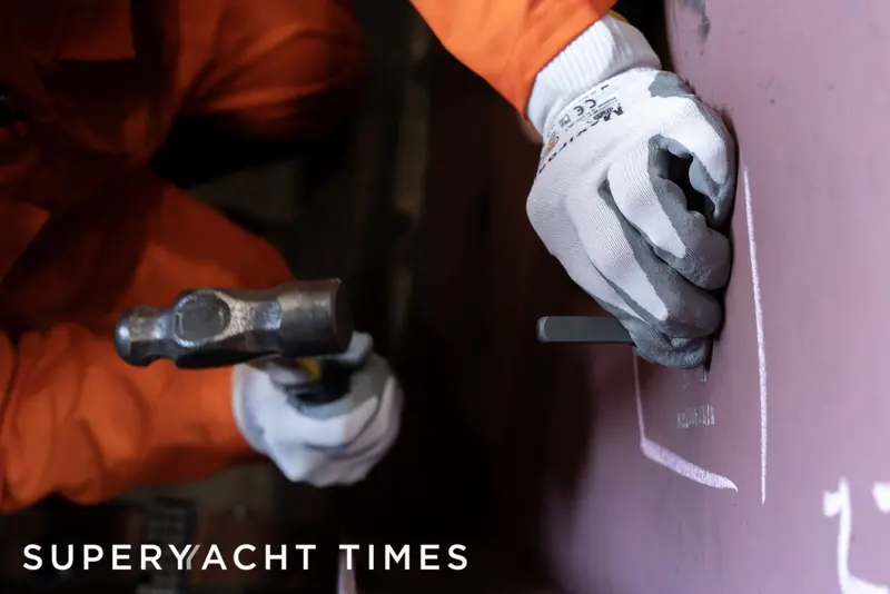 A fitter marks and hammers the keel plate of Project Grace during the December 2024 keel-laying ceremony, held in the presence of a Lloyd's Register surveyor.