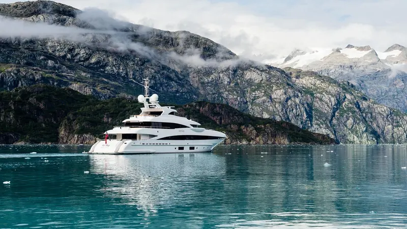 Anchored in a glacial fjord with cloud sitting low on the surrounding peaks, the kind of cold-water cruising ground a steel-and-aluminium Heesen hull is built to handle without the range compromises of a lighter build.