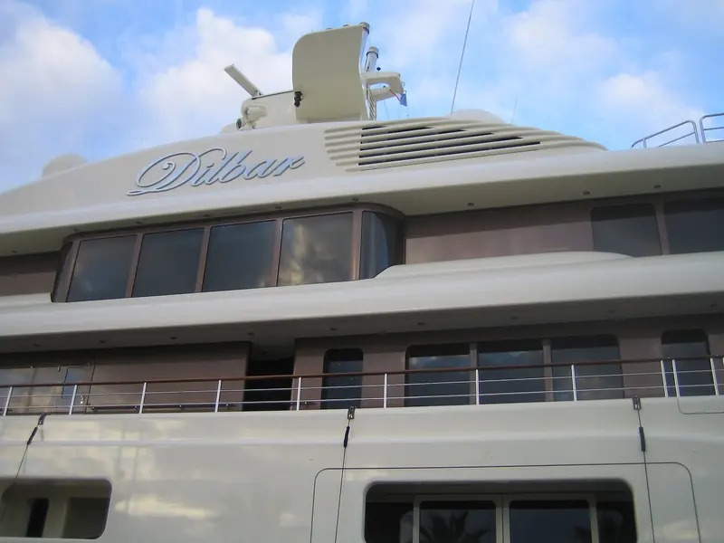 The gold Dilbar script on the superstructure, set below the radar mast and satellite domes that crowd the yacht's upper decks.